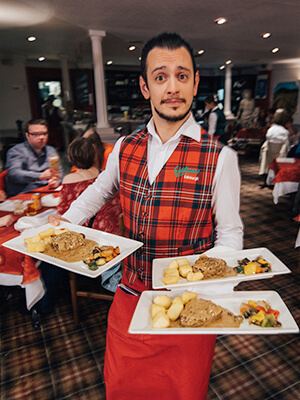 A waiter opening a bottle of wine for customers