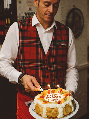 A waiter opening a bottle of wine for customers